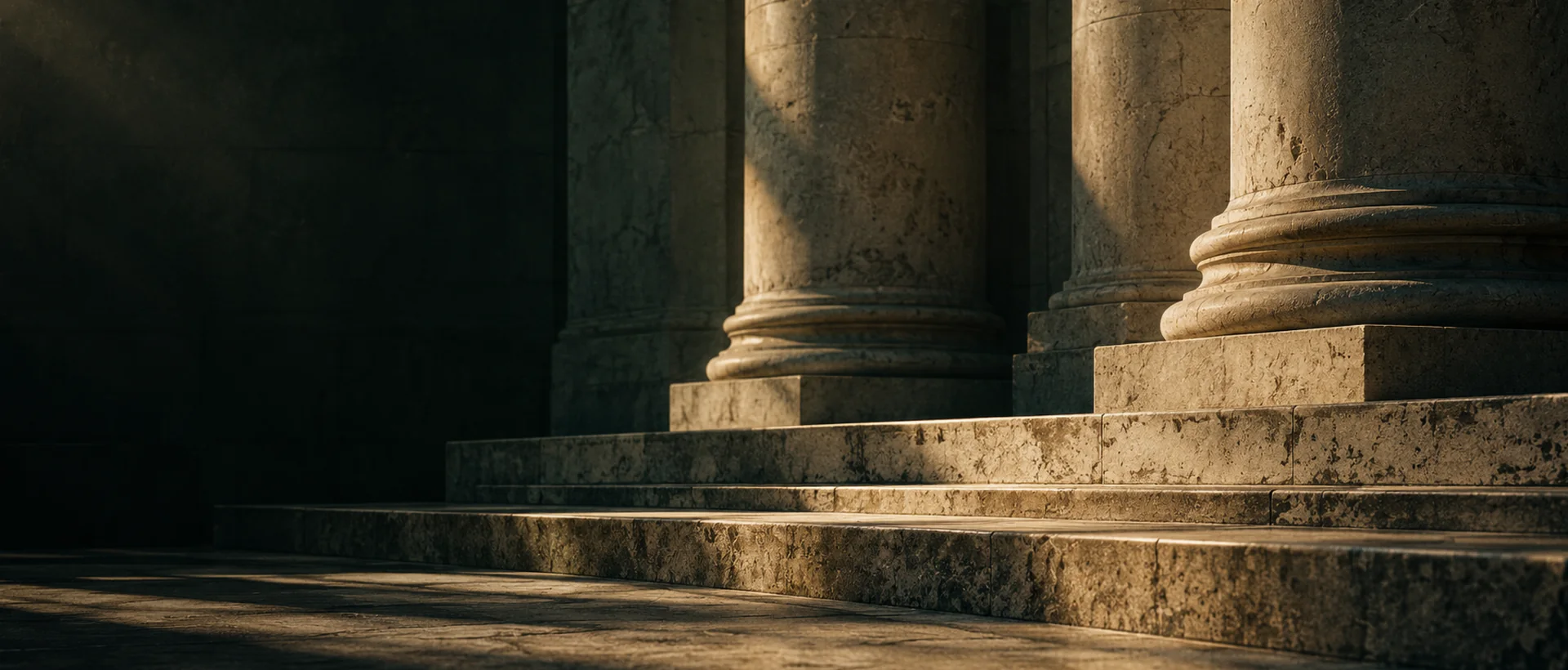 Escadaria e colunas neoclássicas em pedra sob luz lateral, em tons de sombra esverdeada